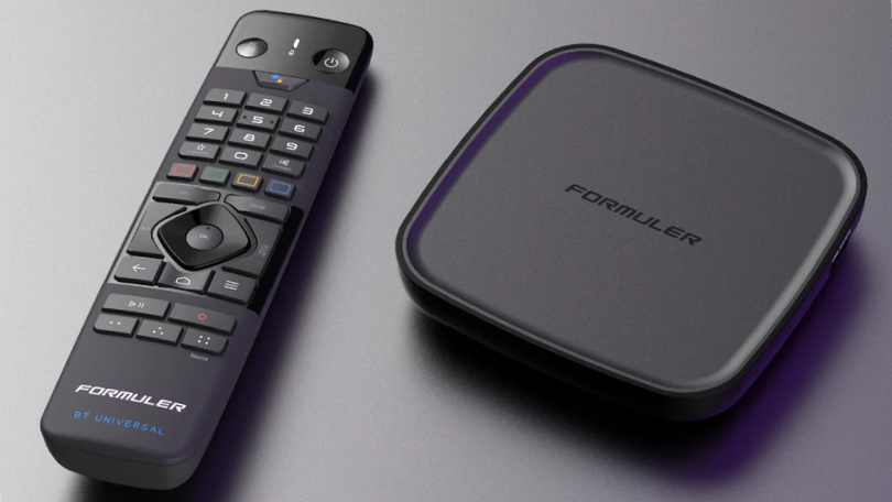 Formuler medie-streamingboks og den tilhørende Bluetooth-universal fjernbetjening på en grå overflade.