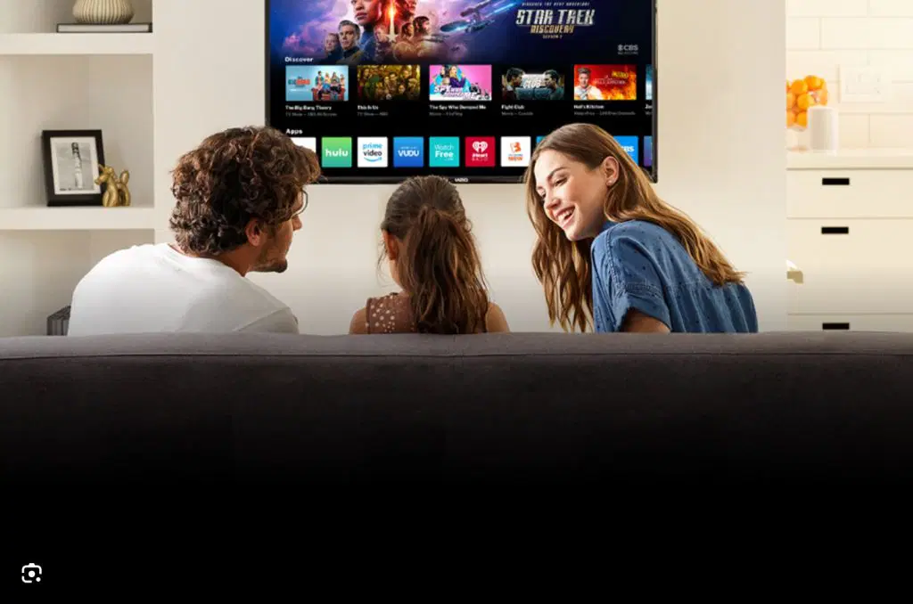 Familie ser Smart TV-streamingmenu med apps fra en sofa i stuen.